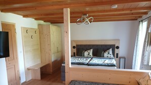 Una habitación con paneles de madera, una cama, un banco y una mesa.