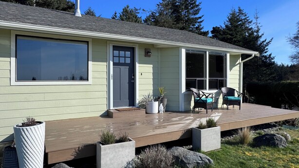 A house with a large deck, a front door, and a window overlooking a grassy area. - Water View Home Near West Beach (Coupeville)