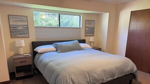 A bedroom with a bed, two bedside tables, a window, and two wall-mounted paintings. - Water View Home Near West Beach (Coupeville)