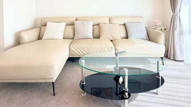 Una sala de estar moderna con un sofá modular, una mesa de centro de cristal y tres cuadros enmarcados en la pared.