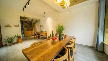 A wooden dining table with chairs, a chandelier, and potted plants.