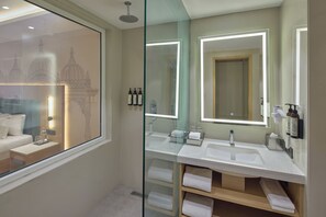 A modern bathroom with a glass shower enclosure, dual sinks, and a large mirror with integrated lighting.