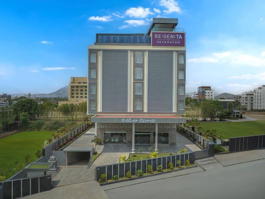 Um hotel moderno com um letreiro que diz 'RE:GEN:TA DEVARAYAH' e uma área de entrada coberta.