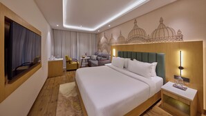 Una habitación de hotel con una cama grande, televisión, escritorio, silla y un mural decorativo en la pared.