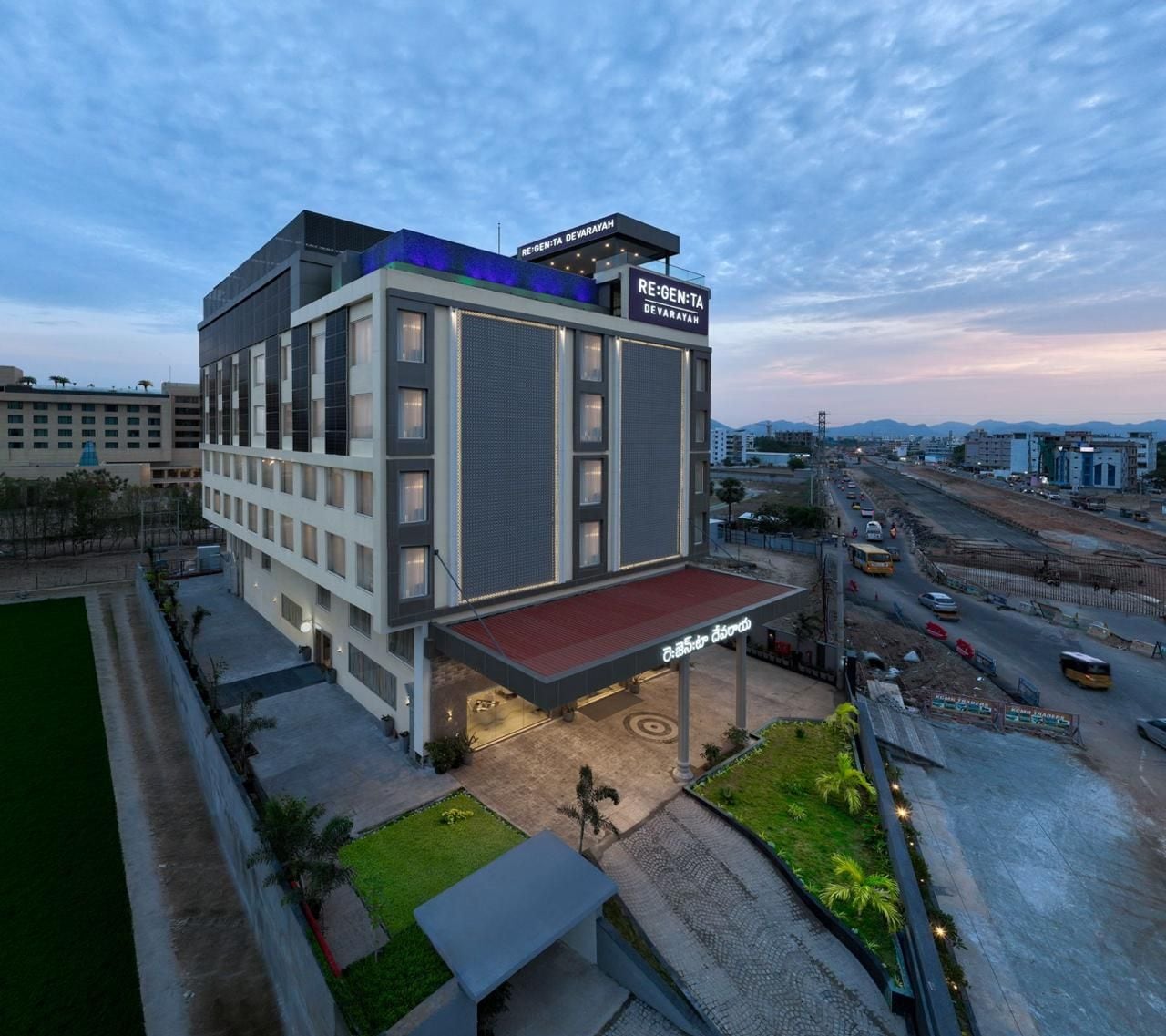 A modern hotel with a flat roof, multiple floors, and a covered entrance area.