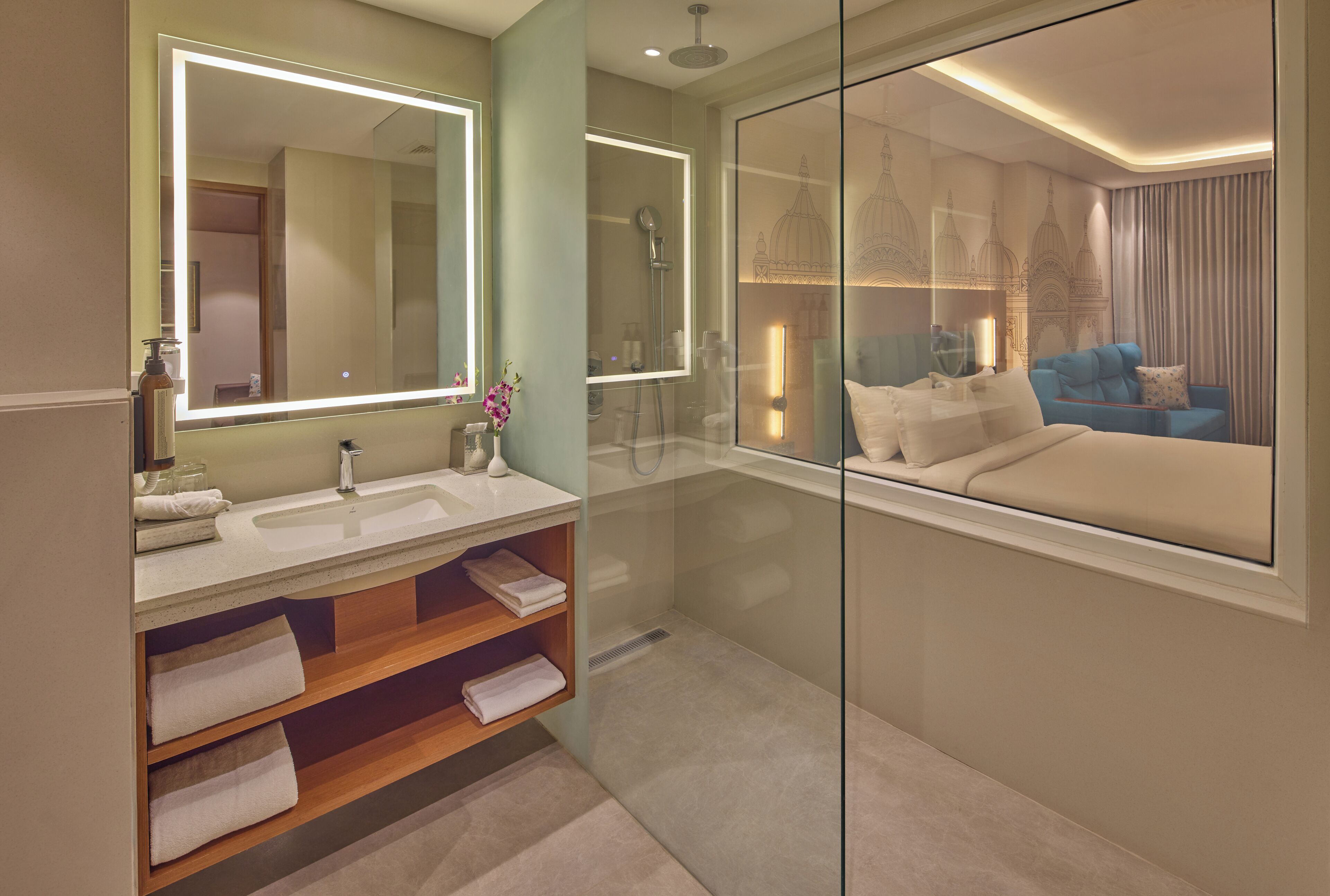 A modern bathroom with a large mirror, a shower, a sink, and a glass partition.