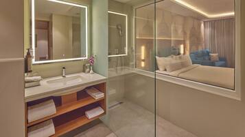 A modern bathroom with a large mirror, a shower, a sink, and a glass partition.
