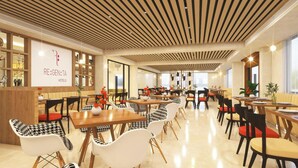 Un restaurante de hotel moderno con paneles de techo de madera, diversas opciones de asientos que incluyen mesas y sillas, y un letrero visible para 'RE:GEN:TA HOTELS'.