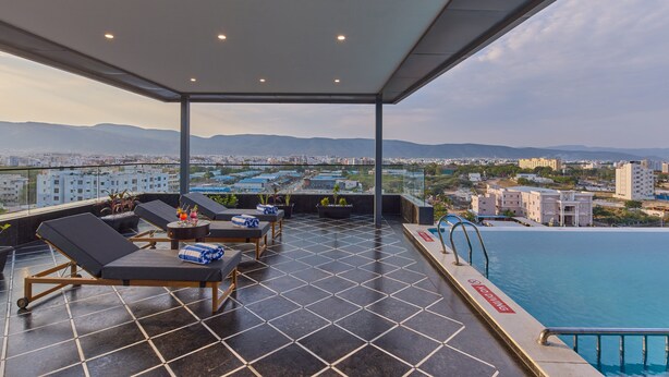 Terraza con sillones, piscina y vista panorámica de la ciudad.