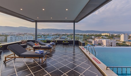 A rooftop lounge with lounge chairs, a pool, and a city view.. Regenta Devarayah Tirupati