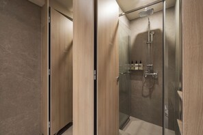 A modern bathroom with a glass-enclosed shower, wooden paneling, and a visible bottle of shampoo. - KANSO STAY (Seoul)