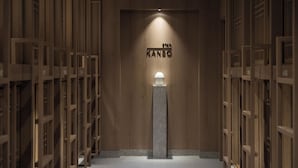 Ein Korridor mit Holzvertäfelung und einer zentralen Säule mit einer Leuchte. Auf der Wand ist der Text 'STAY KANSA' zu sehen.