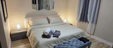 A bedroom with a bed, bedside lamps, a ceiling fan, and a window with curtains.