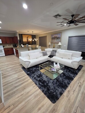 A modern living room with a sectional sofa, a glass coffee table, and a black shag rug. - HOME SWEET HOME (Fort Pierce)