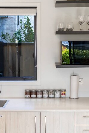 A kitchen with a window, a microwave, and jars on the counter. - Central Townhouse Near One NZ Stadium & Te Pae (Christchurch)