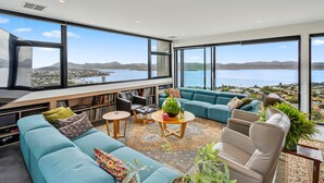 A modern living room with a large sofa, a coffee table, and a bookshelf.