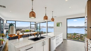 A modern kitchen with a large island, stainless steel appliances, and a view of a lake.