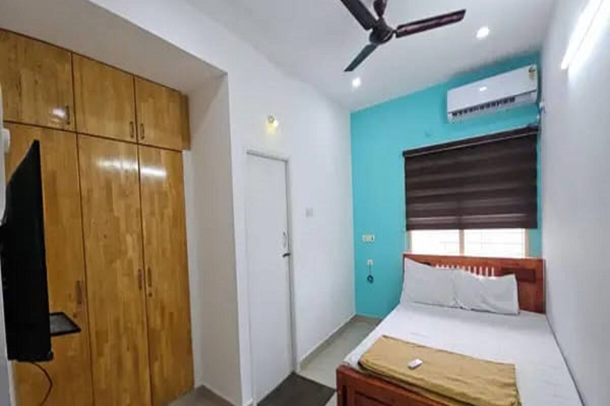 A bedroom with a bed, a ceiling fan, a wardrobe, and an air conditioning unit.