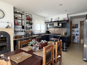 A modern kitchen with a central island, built-in appliances, and a dining area with wooden chairs and a table. - Villa Aura in Platja d'Aro (Castell-Platja d'Aro)