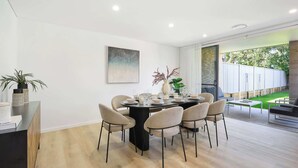 Un coin repas moderne avec une table ronde, six chaises et un vase avec des plantes.