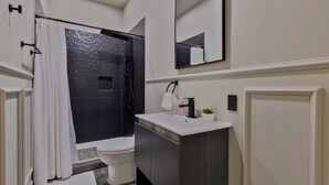 Een moderne badkamer met douche, toilet en wastafel.