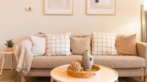 Ein Wohnzimmer mit einer Couch, Kissen, einer Vase und einem kleinen Tisch mit Pflanze und Dekoration.