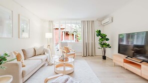 A modern living room with a sofa, coffee table, TV, and a plant. - The Rockley Sunlit Urban Apartment in South Yarra (South Yarra)