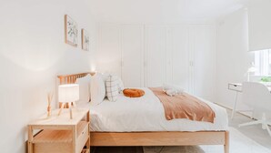 Una camera da letto minimalista con un letto di legno, un comodino, una lampada e una scrivania con sedia.
