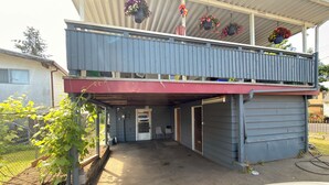Een gebouw met twee verdiepingen, een overdekt terras, een garage en een omheinde tuin.