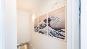 A hallway with a wall-mounted artwork depicting a wave. - Haneda kodate HT3 (Ota)