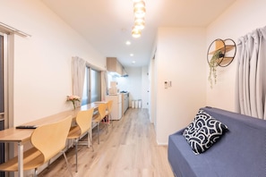 Een compacte kamer met een eethoek, een kitchenette en een bed met een gestreept kussen.