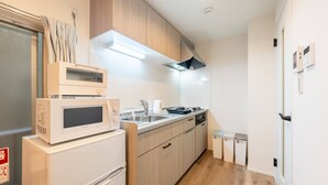 A compact kitchen with a microwave, refrigerator, sink, and wooden cabinets. - Haneda kodate HT3 (Ota)