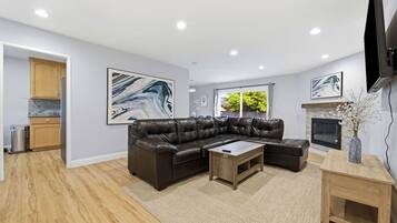 A modern living room with a sectional sofa, a coffee table, and a fireplace.