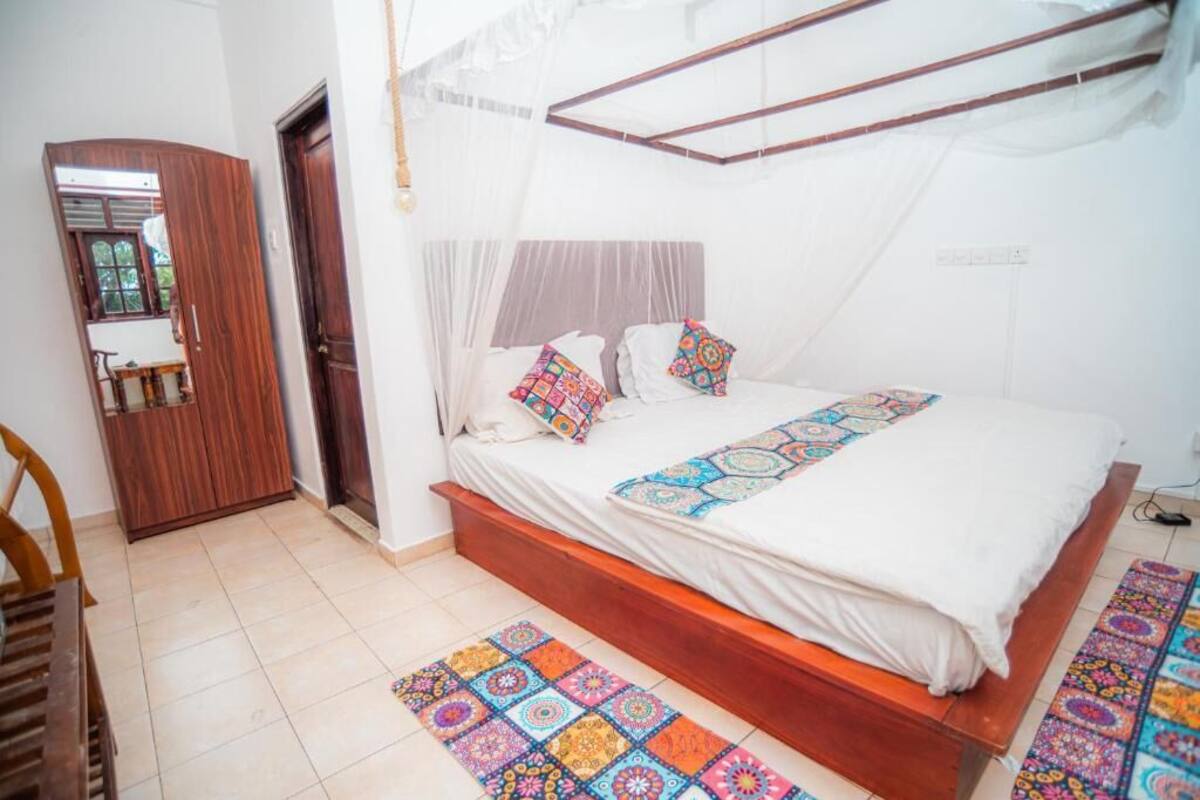 Une chambre à coucher avec un lit, une armoire en bois, un banc et un tapis à motifs.