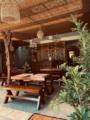 A rustic interior with wooden tables and benches, woven ceiling, and hanging light fixtures. - Prime time hotel (Unawatuna)