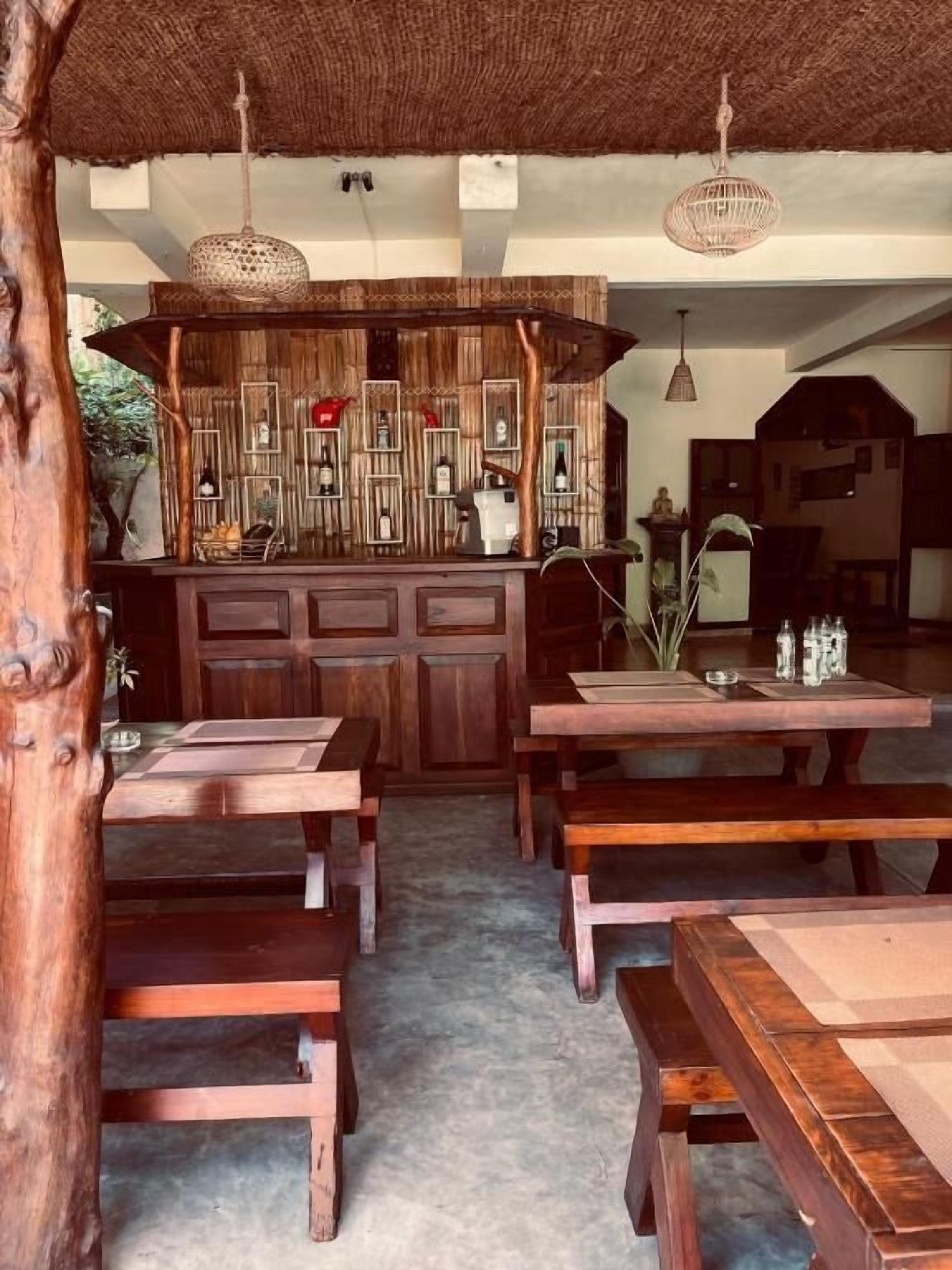 Un coin repas rustique en bois, avec des bancs et un îlot central doté d’étagères.