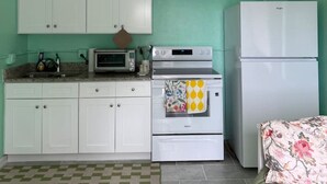 Una cocina compacta con armarios blancos, microondas, horno y refrigerador.