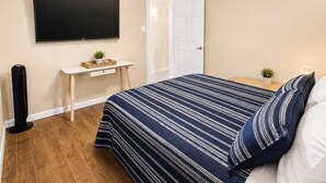 A bedroom with a bed, a desk, a television, and a ceiling fan. - Private Pool Oasis in Quiet Energy Corridor Villa (Houston)