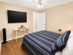 Ein Schlafzimmer mit einem Bett, einem Schreibtisch, einem Fernseher und einem Deckenventilator.