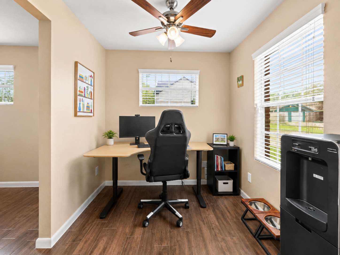 A home office with a desk, chair, computer, and a ceiling fan.