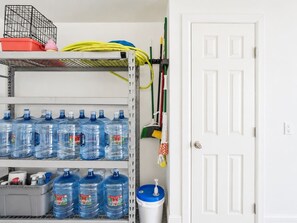 Ein Lagerraum mit Regalen, auf denen große Wasserkrüge und Reinigungsmittel stehen.