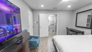 A hotel room with a bed, a TV, a desk, and a chair. - 4BR Workspace Home | 2.5 Baths | Sleeps 8 (Houston)