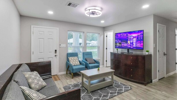 A living room with a sofa, two armchairs, a coffee table, a TV, and a cabinet. - 4BR Workspace Home | 2.5 Baths | Sleeps 8 (Houston)