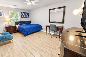 A bedroom with a bed, a desk, a chair, a dresser, a mirror, and a ceiling fan. - 4BR Workspace Home | 2.5 Baths | Sleeps 8 (Houston)