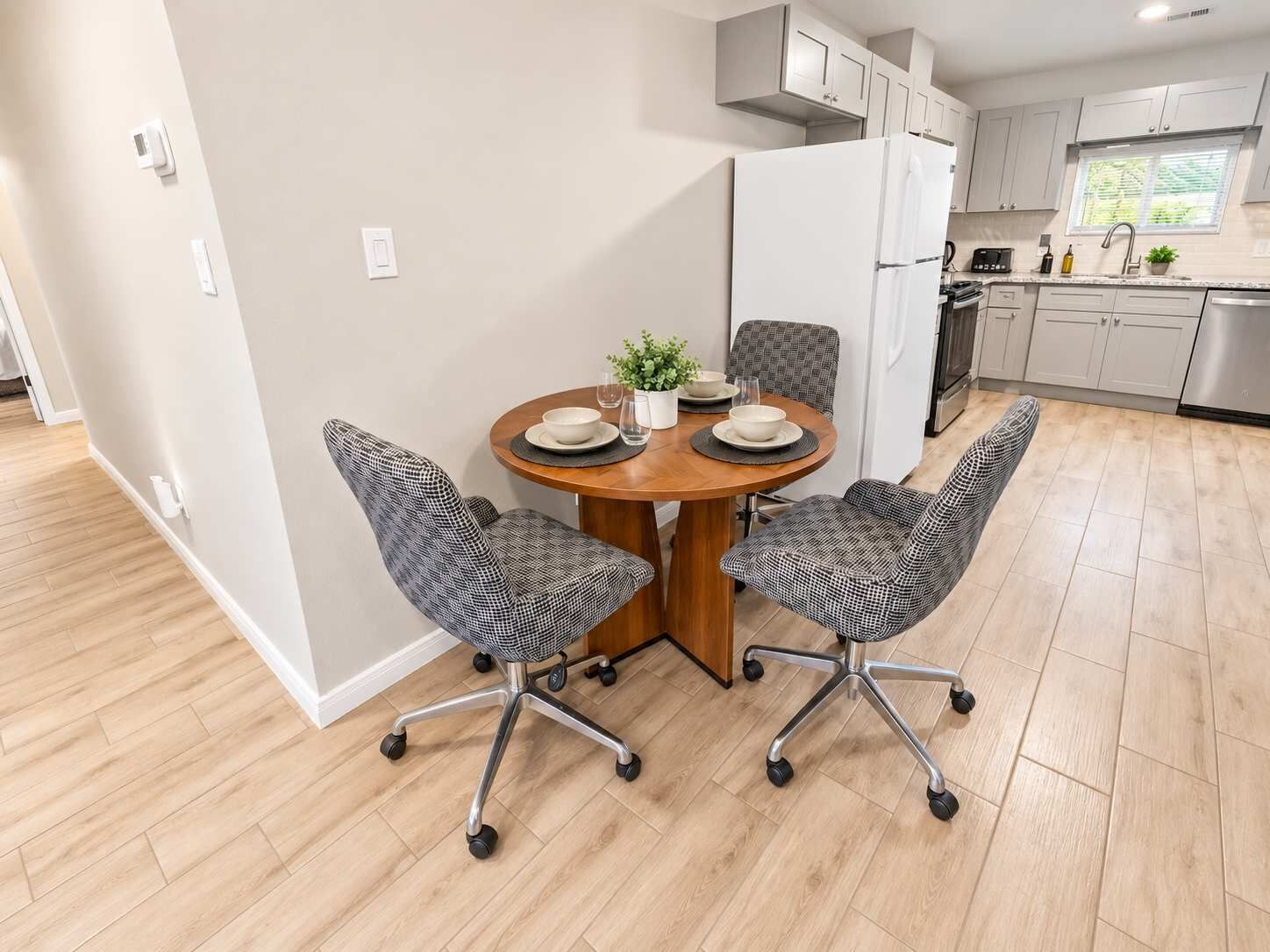 A modern kitchen with white cabinets, a built-in oven, and a stainless steel refrigerator.