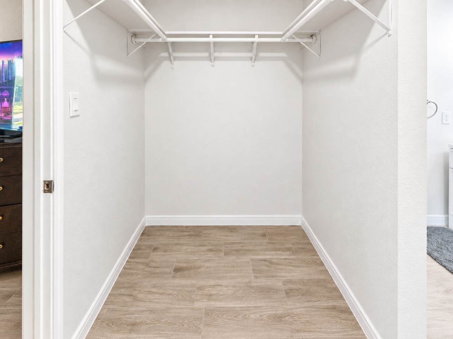Um closet amplo com piso de madeira, paredes brancas e teto branco.