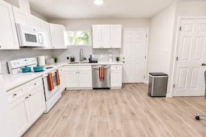 A modern kitchen with white cabinetry, a stainless steel dishwasher, and a trash can. - Renovated Home w/ Workspaces, Near Hobby Airport (Houston)