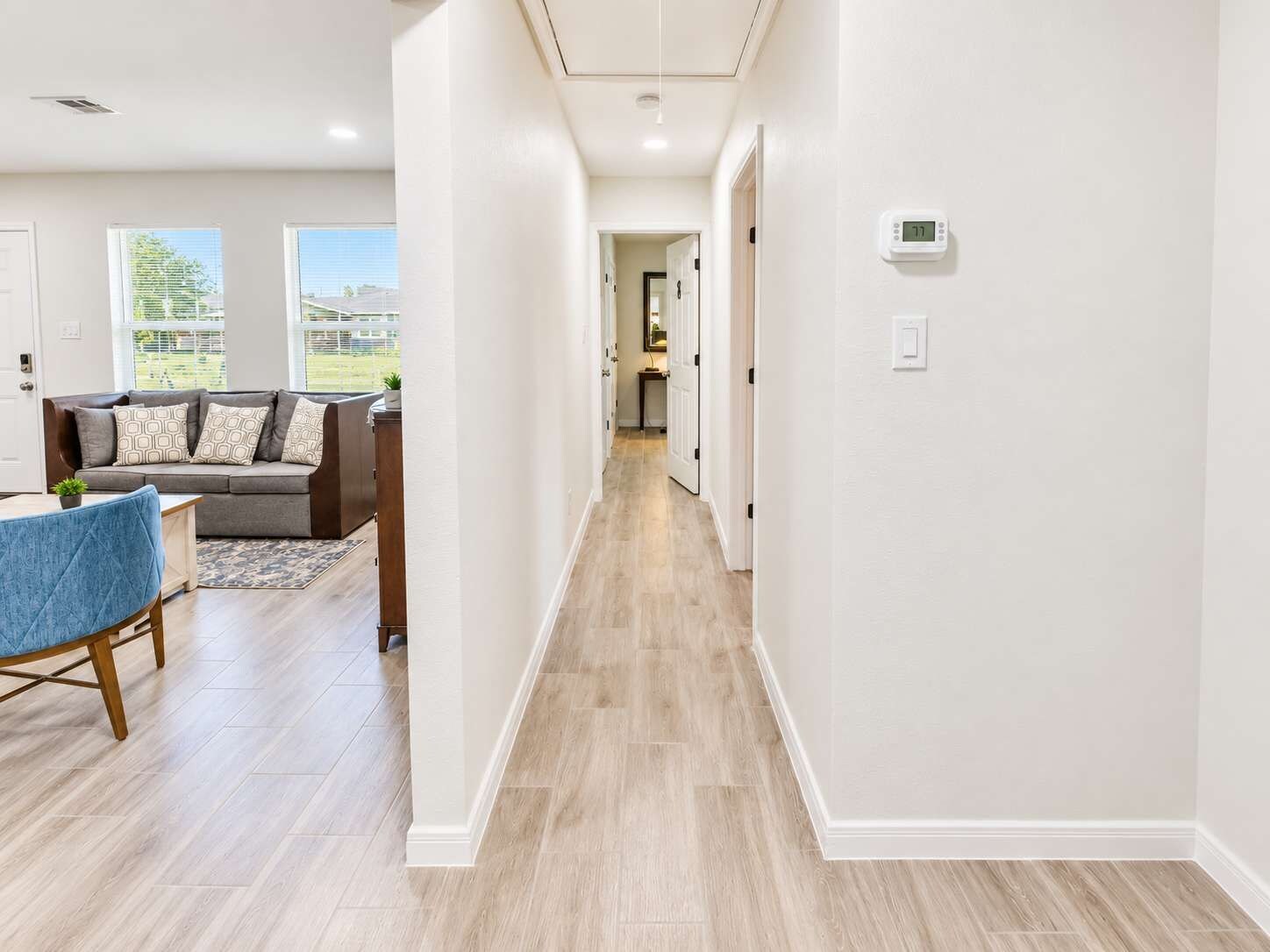 A modern interior with a hallway leading to a living area and kitchen.