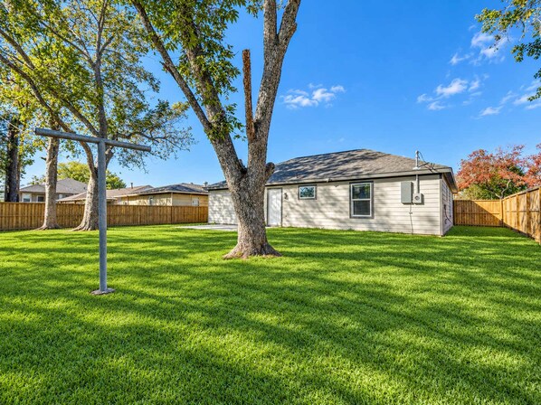 A residential property with a well-maintained lawn, a single-story house, and a wooden fence.
