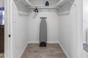 A compact room with a built-in ironing station, a small shelf, and a door leading to another area. - Renovated Home w/ Workspaces, Near Hobby Airport (Houston)